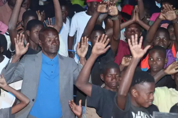 Villagers at an outdoor crusade screening in Mozambique raising their hands